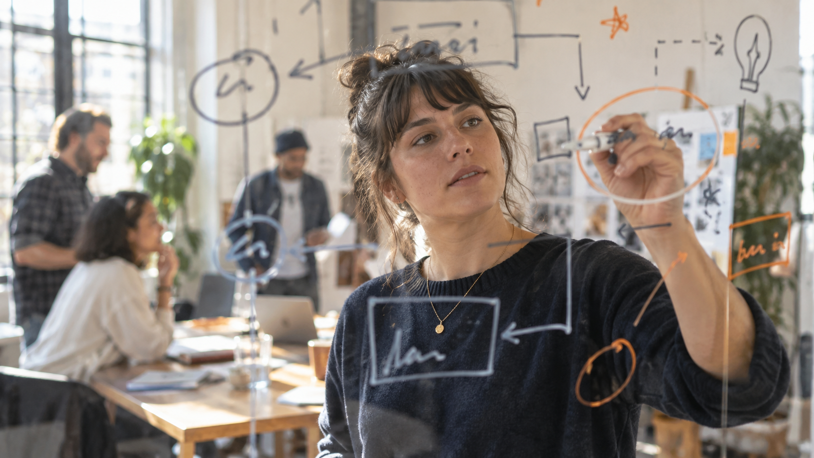 Participant mapping ideas on a glass whiteboard